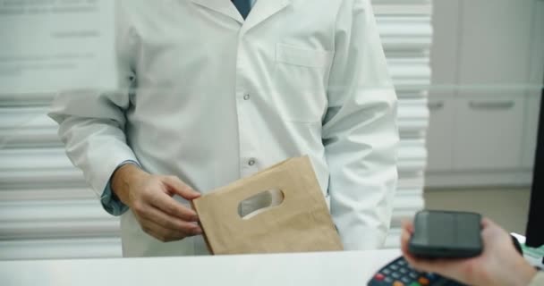 Apotek apotek kassan Counter: Apotek och en kund som använder NFC Smartphone med kontaktlös betalterminal för att köpa receptbelagd medicin, hälso-och sjukvård varor. Närbild Skott — Stockvideo