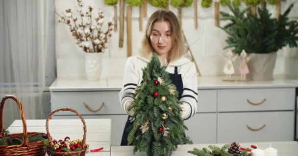 Florist at work. Woman florist make beautiful Christmas decoration in fir shape, small Christmas tree — 图库视频影像