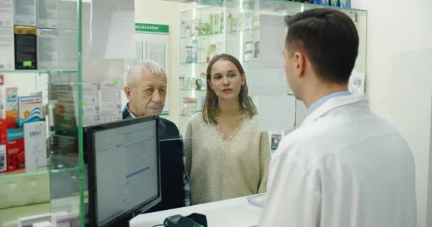 Η κόρη βοηθά τον πατέρα της, συνταξιούχο, να αγοράσει φάρμακα από το φαρμακείο. Απεριόριστη αγορά φαρμάκου σε φαρμακείο. Βοηθήστε τον συνταξιούχο — Αρχείο Βίντεο