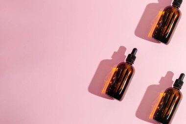Kozmetik şişeleri pembe arka planda üç parça, izole edilmiş, minimalizm. Kozmetoloji, tedavi.