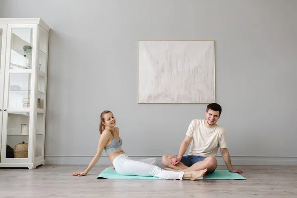 Evde paspasın üzerinde akro yoga yapan genç bir çift. Egzersiz sonrası dinlenme.
