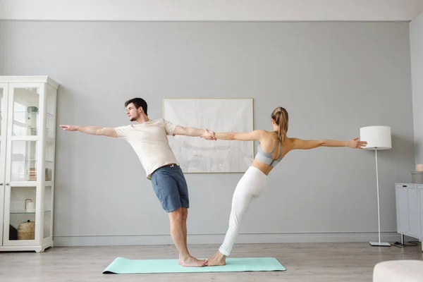 Pareja joven practicando acro yoga sobre estera en la casa juntos. Deportes en casa —  Fotos de Stock