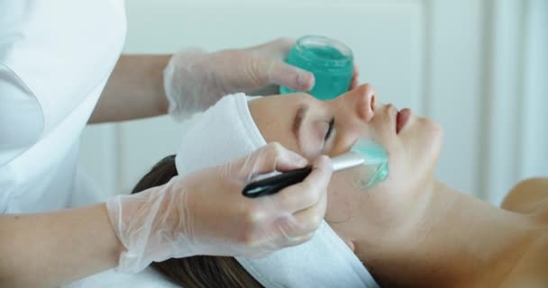 Een mooie vrouw krijgt een blauwe verfrissende anti-aging gel. Schoonheidsspecialiste procedures. Close-up — Stockvideo