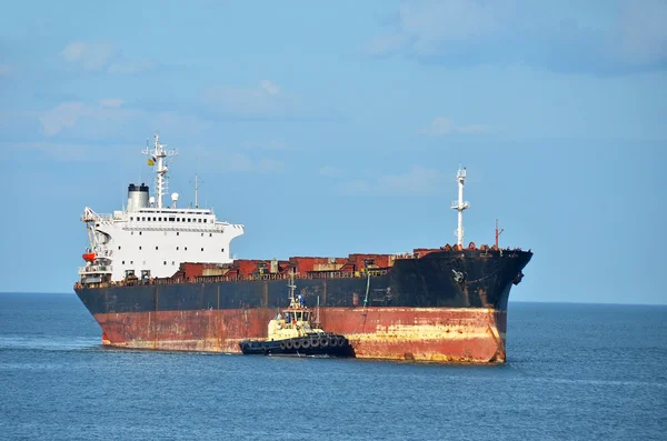 Tugboat assisting cargo ship — Stock Photo, Image