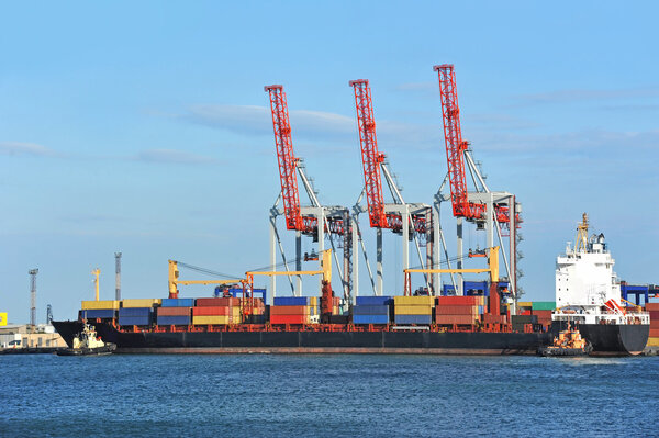 Tugboat assisting container cargo ship