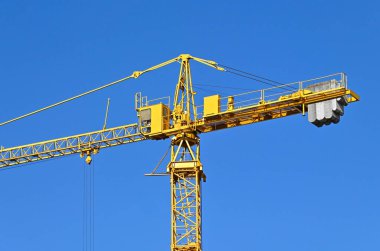 Mavi gökyüzüne karşı yüksek inşaat kulesi vinci