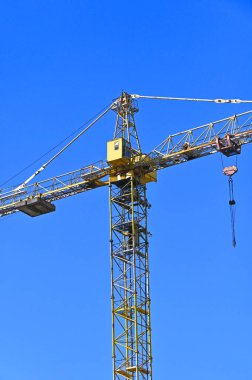 Mavi gökyüzüne karşı yüksek inşaat kulesi vinci