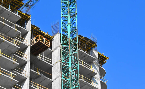 Crane and building under construction against blue sky