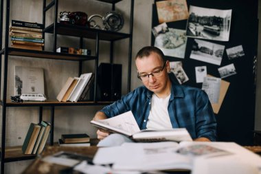 Gözlüklü genç adam ofiste şık bir ofis tarzı kitap okuyor.