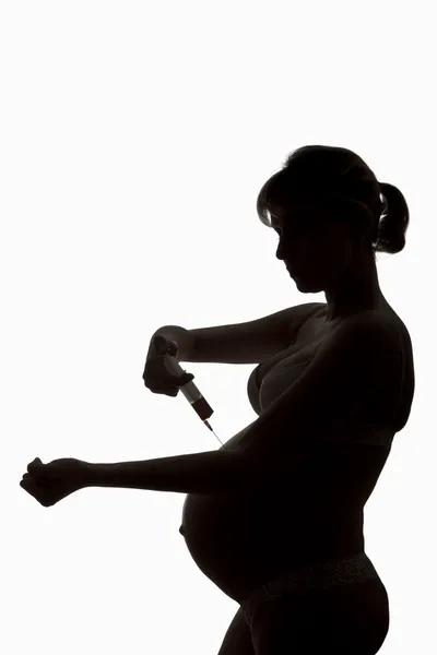 Silhouette di donna incinta con siringa in mano — Foto Stock