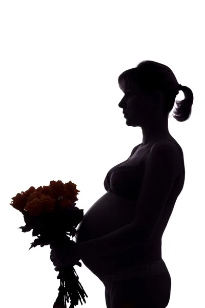 Silhouette of the 33-week pregnant woman with a bouquet of roses — Stock Photo, Image