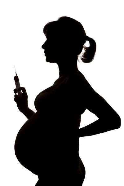 Silhouette of the pregnant woman with a syringe in a hand — Stock Photo, Image