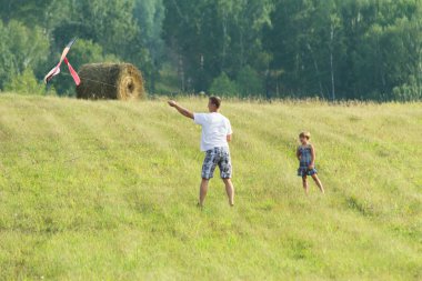 The young father with the daughter on meadow let in kite flight