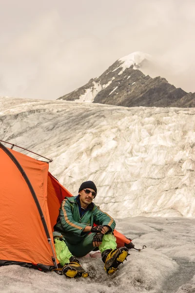 Скалолаз в палатке смотрит на вершины гор — стоковое фото