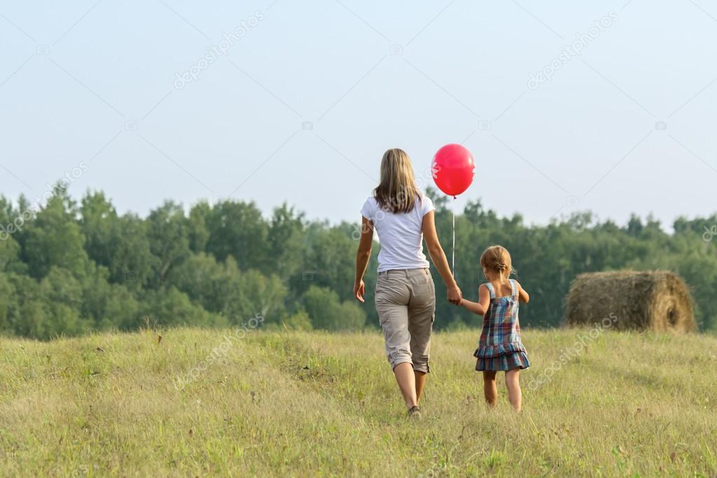 Mother and daughter go from the camera in ibeautiful field
