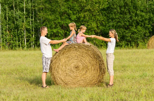 Happy family with child on haystack in sunny day — Stock Photo, Image