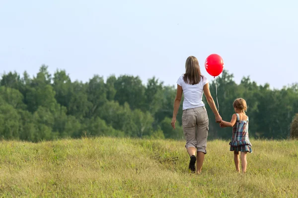 La jeune mère avec l'enfant traverse le champ. Extérieur . — Photo