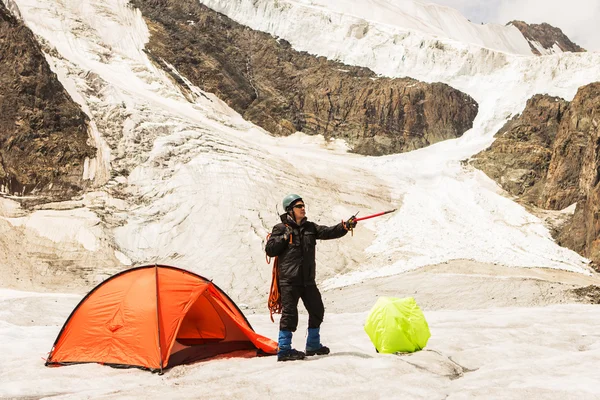 Альпинист, стоящий у палатки на леднике — стоковое фото