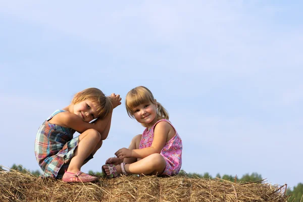 Deux filles s'assoient sur une botte de foin — Photo