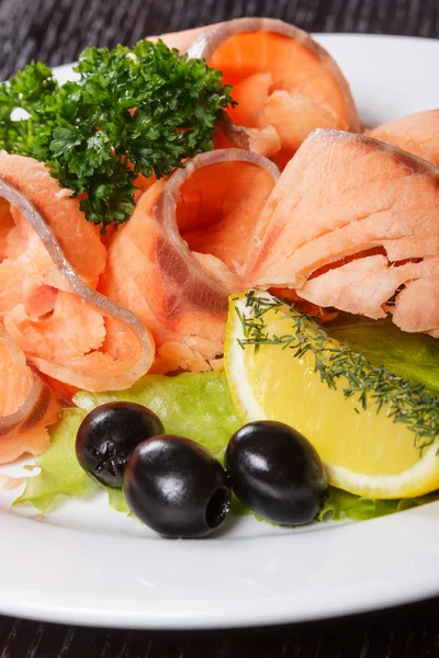 Кусочки красной рыбы с лимоном и оливками на тарелке — стоковое фото