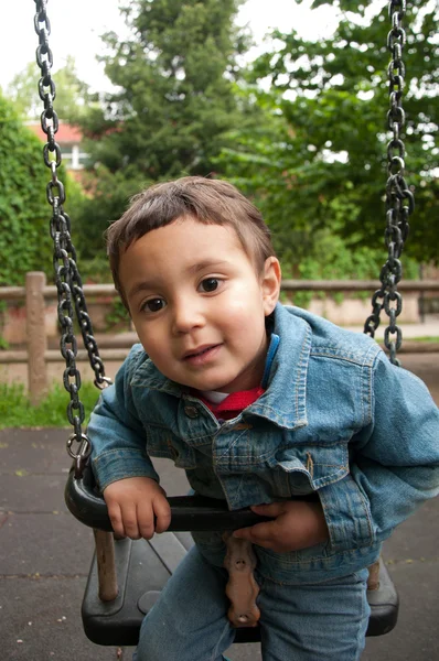 Weinig schattige jongen spelen op een schommel — Stockfoto