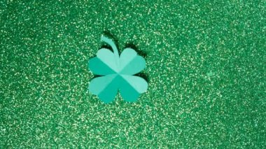 Aziz Patrick Günü. Kağıttan kesilmiş bir yonca yaprağı parlak yeşil bir arka planda dönüyor. Yüksek kalite 4k görüntü