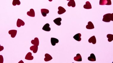 Sevgililer Günü konsepti. Kırmızı kalp şeklinde pullar pembe arka planda daire çiziyor. Yüksek kalite 4K görüntü.
