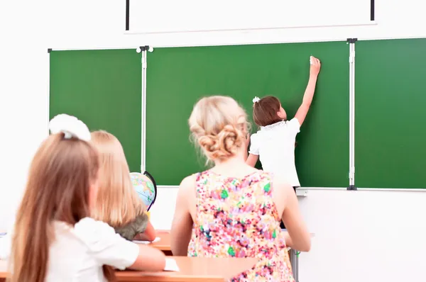 School girl writes on the blackboard — Stock Photo, Image
