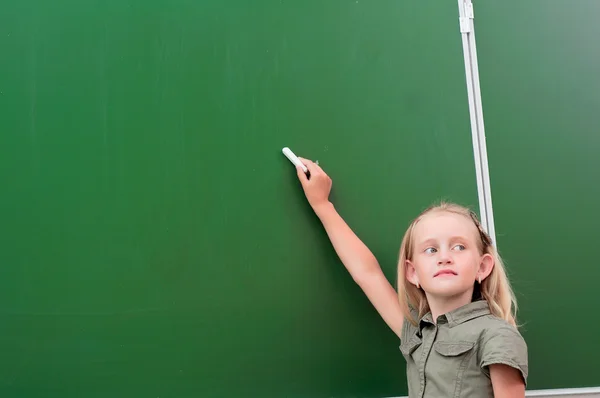 Écolière écrit sur un tableau noir — Photo