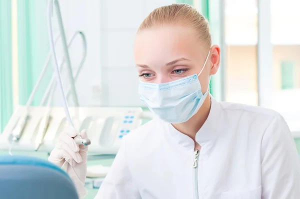 Dentistas femininos em máscara protetora detém uma broca dentária — Fotografia de Stock