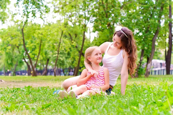 Mor och dotter sitter tillsammans på gräset — Stockfoto