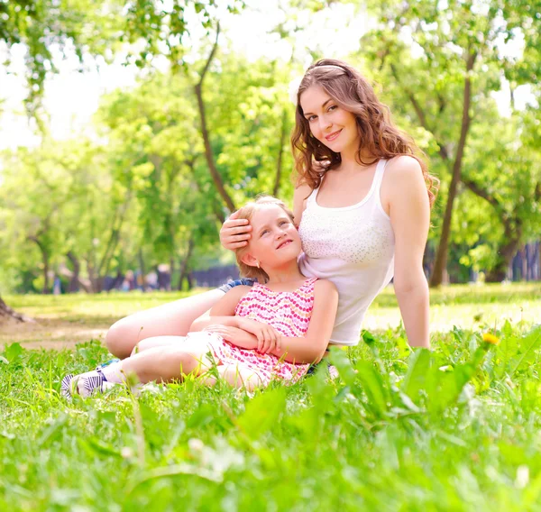 Mor och dotter sitter tillsammans på gräset — Stockfoto