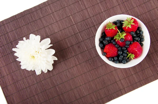 Erdbeeren, Heidelbeeren und Blume auf Bambus-Tischdecke — Stockfoto
