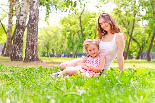 Anne ve kızı birlikte çimlerde oturan — Stok fotoğraf