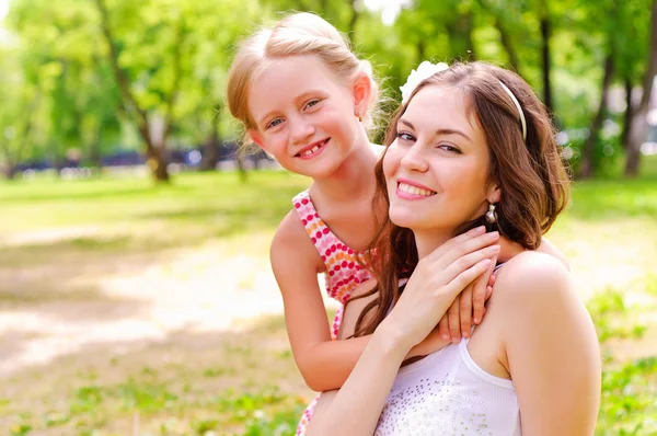 Anne ve kızı birlikte çimlerde oturan — Stok fotoğraf