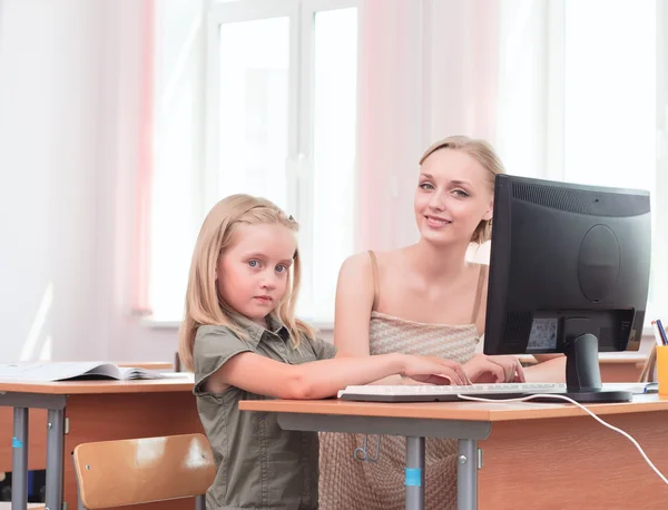 Учитель объясняет задачу школьницы за компьютером — стоковое фото