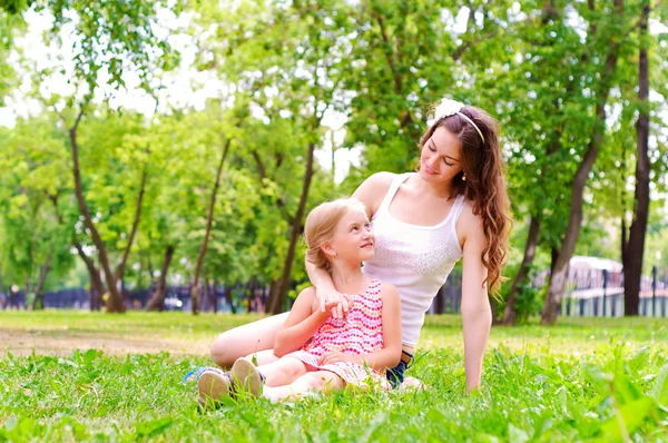 Anne ve kızı birlikte çimlerde oturan — Stok fotoğraf