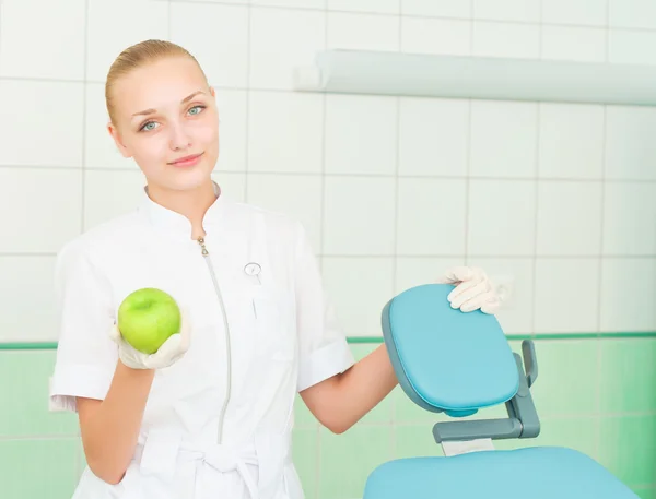 Female dentists shows green apple — Stock Photo, Image