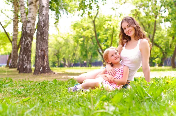 Мать и дочь сидят вместе на траве — стоковое фото