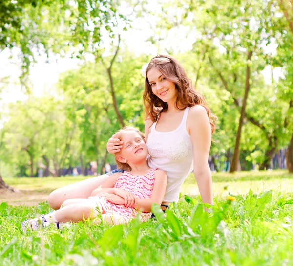 Mãe e filha sentadas juntas na grama — Fotografia de Stock