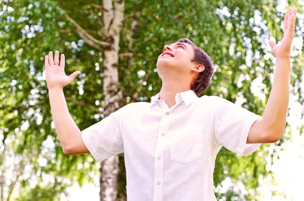 Junger Mann blickt in den Himmel und hält die Hände in die Höhe — Stockfoto