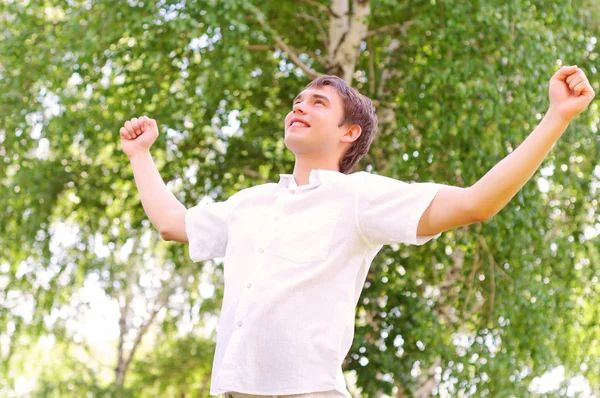 Молодой человек смотрит в небо, держа руки вверх — стоковое фото