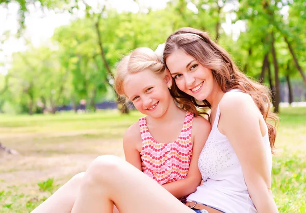 Mère et fille assises ensemble sur l'herbe — Photo