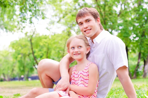 Father and daughter sitting together on the grass — Stock Photo, Image
