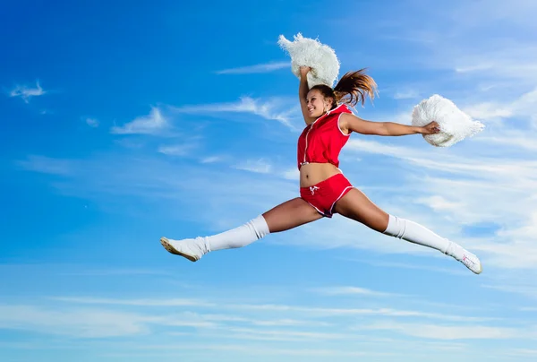 Jovem cheerleader em vermelho traje saltando — Fotografia de Stock