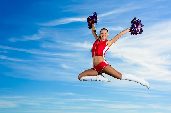 Młoda cheerleaderka w czerwony strój Skoki — Zdjęcie stockowe