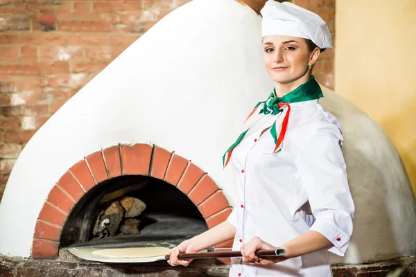 Chef-kok zet deeg in de oven voor pizza 's, — Stockfoto