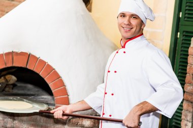 Şef, pizza fırını hamur koyar.,