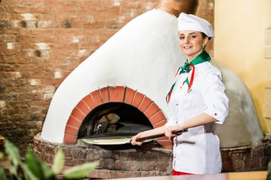 Şef, pizza fırını hamur koyar.,