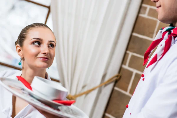 Kelner tar med en tallerken til en hyggelig kvinne. – stockfoto